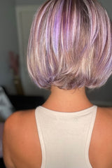 A person with a short, stylish bob haircut featuring shades of lavender and platinum, wearing a beige tank top.
