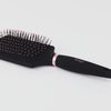 Zoomed in video black Siena Paddle Brush features black nylon bristles with blush L'ange logo