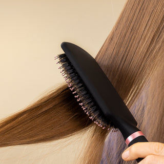 A woman's hair is being brushed by the black boar bristle brush in this close-up.