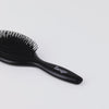 Zoomed in video of Black Beech Wood Oval brush with firm & flexible black bristles with white L’ange logo