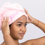 A woman positions the pink, microfiber hair wrap on her head so you can see what it looks like.