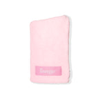 The baby pink microfiber hair towel is folded up with the logo showing.