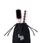 The black tool bag has two styling tools sticking out of the top with the drawstrings pulled tight.