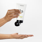 Medium skin hands squeezing white bottle with Treatment A Deux Hair & Scalp Masque in black font